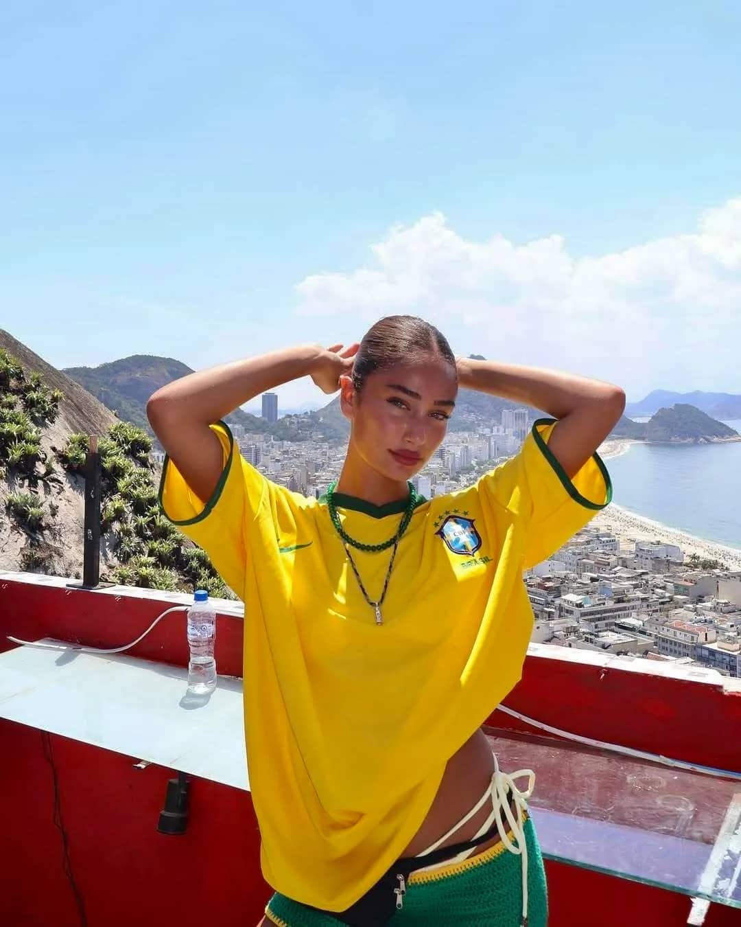 Femme portant le maillot jaune du Brésil sur un bateau, Rio de Janeiro en arrière-plan