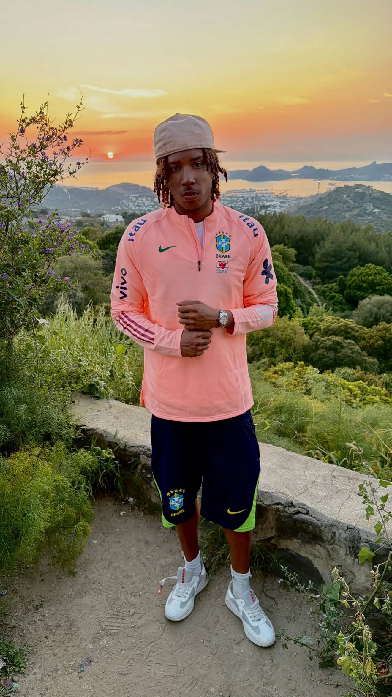 Homme portant un pull zippé Drip Seleção au coucher du soleil, face à la baie de Rio