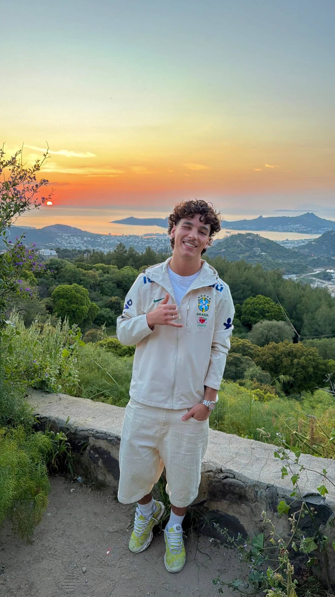 Homme portant la veste du Brésil beige au coucher du soleil, face à la baie
