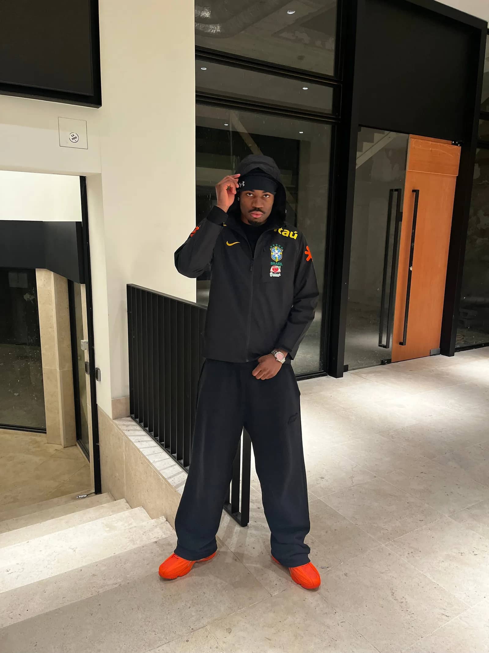 Homme portant la veste imperméable du Brésil noire avec le bas de survêtement assorti